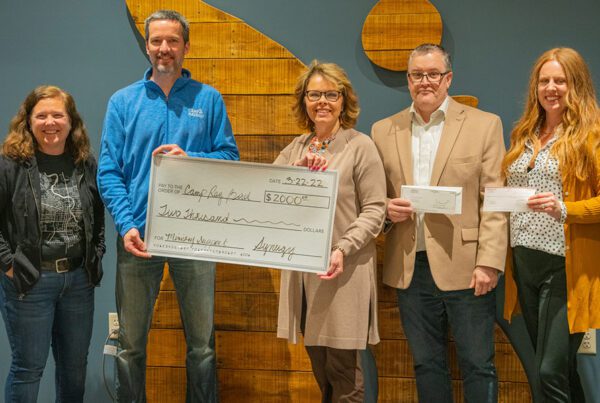 Blog - Synergy Insurance Group Team Presenting the Ray Bird Ministries Non-Profit with a Donation of $2000 While They all Stand Together and Smile for a Photo