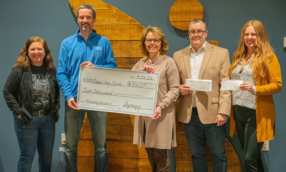 Blog - Synergy Insurance Group Team Presenting the Ray Bird Ministries Non-Profit with a Donation of $2000 While They all Stand Together and Smile for a Photo