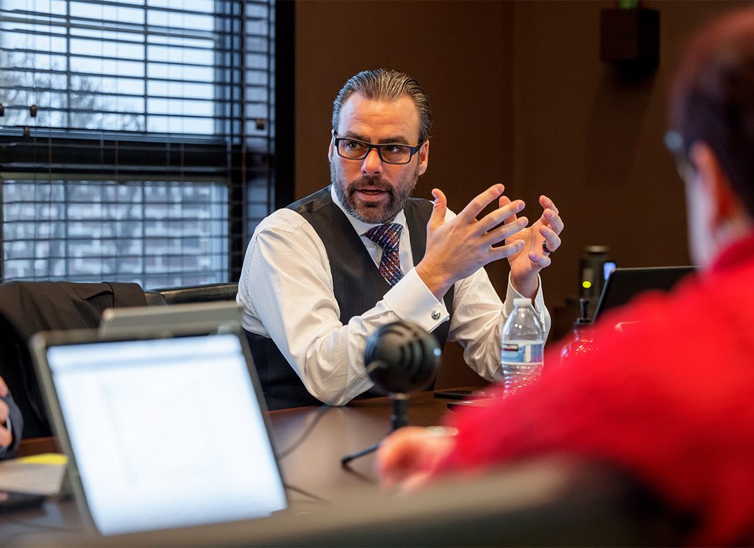 About Our Agency - View of a Mature Man in Formal Wear Having a Discussion During a Business Meeting in the Synergy Insurance Office with Open Laptops on the Desk