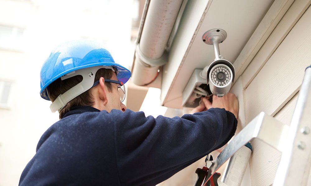 Security camera tips for your business blog - man installing camera on side of building